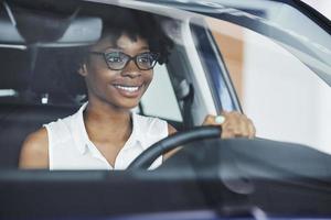 Young african american woman sits inside of new modern car photo