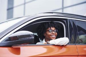 Young african american woman sits inside of new modern car photo