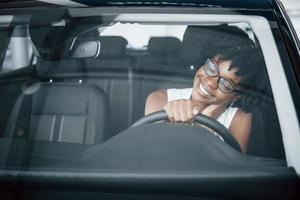 Young african american woman sits inside of new modern car photo