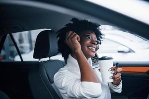 Young african american woman sits inside of new modern car photo