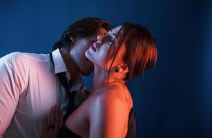 Beautiful man with his hot girlfriend is in the studio with blue neon lighting. Couple in love with each other photo