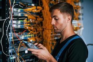 Young man in uniform have a job with internet equipment and wires in server room photo