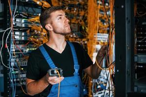 Young man in uniform have a job with internet equipment and wires in server room photo