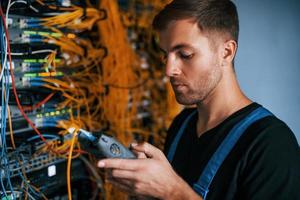 Young man in uniform have a job with internet equipment and wires in server room photo