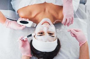 Close up view of woman that lying down in spa salon and have face cleaning procedure by different devices and mask photo