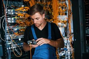 Young man in uniform have a job with internet equipment and wires in server room photo