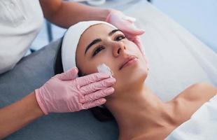 Close up view of woman that lying down in spa salon and have face cleaning procedure by the mask photo