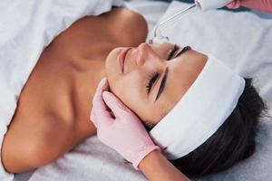 Close up view of woman that lying down in spa salon and have face cleaning procedure by using modern device photo