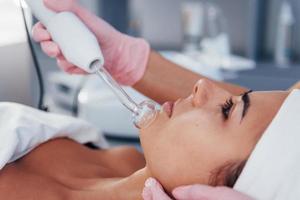 Close up view of woman that lying down in spa salon and have face cleaning procedure by using modern device photo