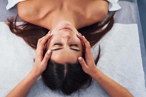 Close up view of woman that lying down in spa salon and have face massage photo