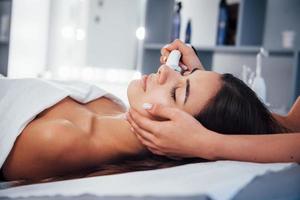 vista de cerca de la mujer que se acuesta en el salón de spa y tiene un procedimiento de limpieza facial foto