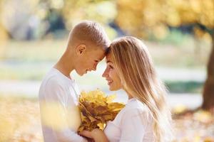 Mother with son have a rest in an beautiful autumn park at sunny day photo