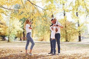 Cheerful young family have a walk in an autumn park together photo