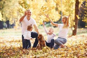 una familia joven y alegre da un paseo juntos por un parque de otoño foto