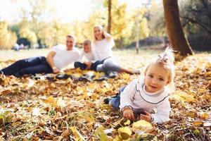 Cheerful young family lying down on the ground and have a rest in an autumn park together photo