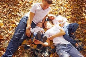 vista superior de la alegre familia joven que descansa juntos en un parque de otoño foto