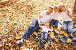 vista superior de la alegre familia joven que descansa juntos en un parque de otoño foto