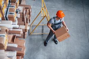 vista superior del trabajador masculino en el almacén con caja en las manos foto