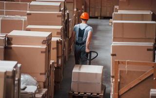 Young male worker in uniform is in the warehouse with pallet truck photo