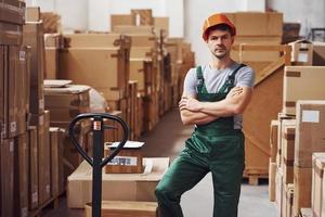 Young male worker in uniform is in the warehouse with pallet truck photo