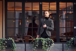 Man in elegant formal wear outside against modern building photo