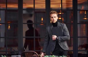 Man in elegant formal wear outside against modern building photo