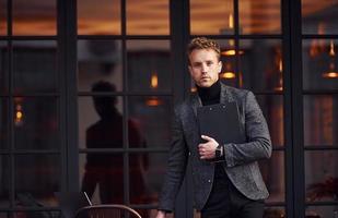 Man in elegant formal wear outside against modern building photo