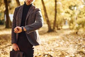 Close up view of young man in formal clothes that is in the autumn park at sunny day photo