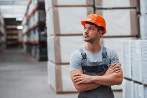 retrato de joven trabajador en uniforme que está en almacén foto