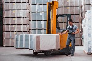 Portrait of young worker in unifrorm that is in warehouse near forklift photo