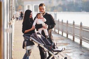 familia alegre con cochecito pasea junto con su hijo en el parque foto