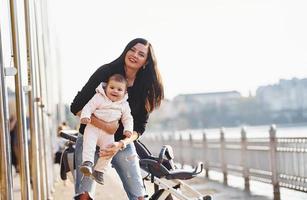 Mother with pram in casual clothes with her child is in the park photo