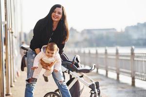 Mother with pram in casual clothes with her child is in the park photo