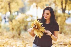 retrato de morena que se divierte con hojas en el hermoso parque de otoño foto
