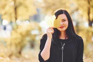 Portrait of brunette that have fun with leaves in beautiful autumn park photo