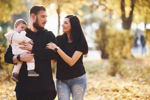 familia alegre divirtiéndose junto con su hijo en el hermoso parque de otoño foto