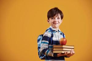 Portrait of young smart schooler in the studio against yellow background photo