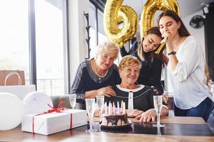 globos con el número 60. mujer mayor con familiares y amigos celebrando un cumpleaños en el interior foto