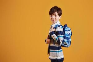 Portrait of young smart schooler in the studio against yellow background photo