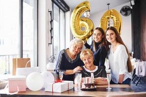 globos con el número 60. mujer mayor con familiares y amigos celebrando un cumpleaños en el interior foto