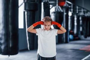 retrato de una niña pequeña con ropa deportiva que está en el gimnasio tiene un día de ejercicio. concepción del boxeo foto