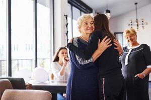 Embracing each other. Senior woman with family and friends celebrating a birthday indoors photo