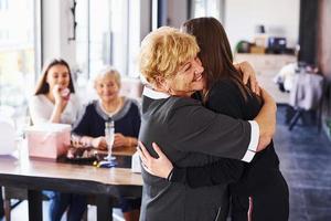 Embracing each other. Senior woman with family and friends celebrating a birthday indoors photo