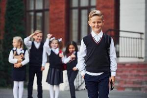 grupo de niños con uniforme escolar posando juntos para la cámara al aire libre cerca del edificio educativo foto