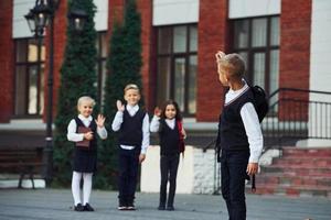 grupo de niños con uniforme escolar posando juntos para la cámara al aire libre cerca del edificio educativo foto