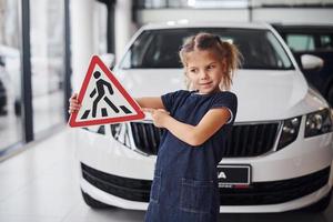 retrato de una linda niña que tiene señales de tráfico en las manos en el salón del automóvil foto