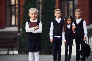 grupo de niños con uniforme escolar posando juntos para la cámara al aire libre cerca del edificio educativo foto