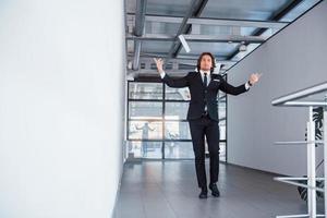 Throwing papers into the air. Portrait of handsome young businessman in black suit and tie photo