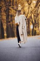 Portrait of young brunette that have a walk on road in autumn forest at daytime photo