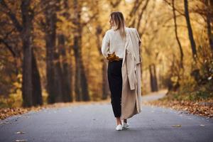 Portrait of young brunette that have a walk on road in autumn forest at daytime photo